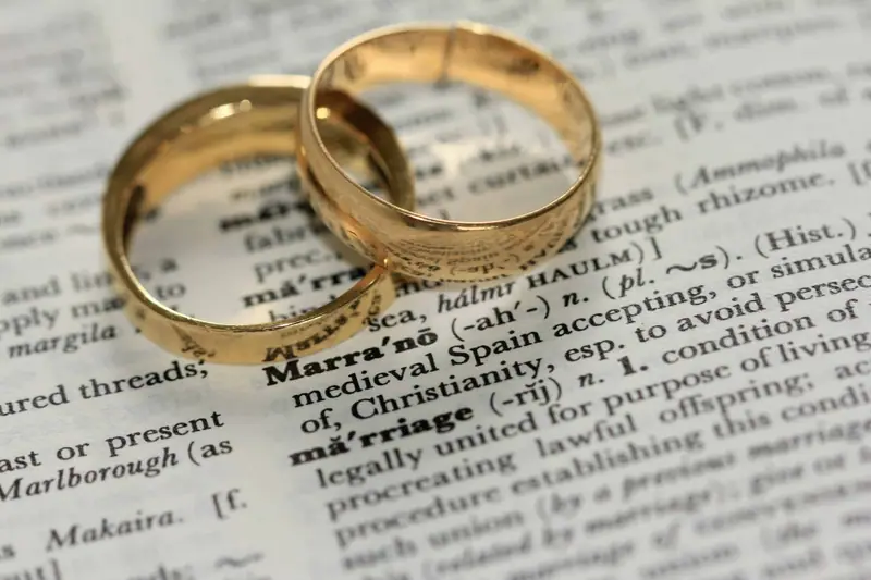 Two gold wedding bands lying on a dictionary page