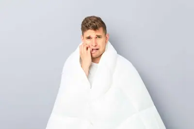 Nervous groom wrapped in a white duvet biting his thumb